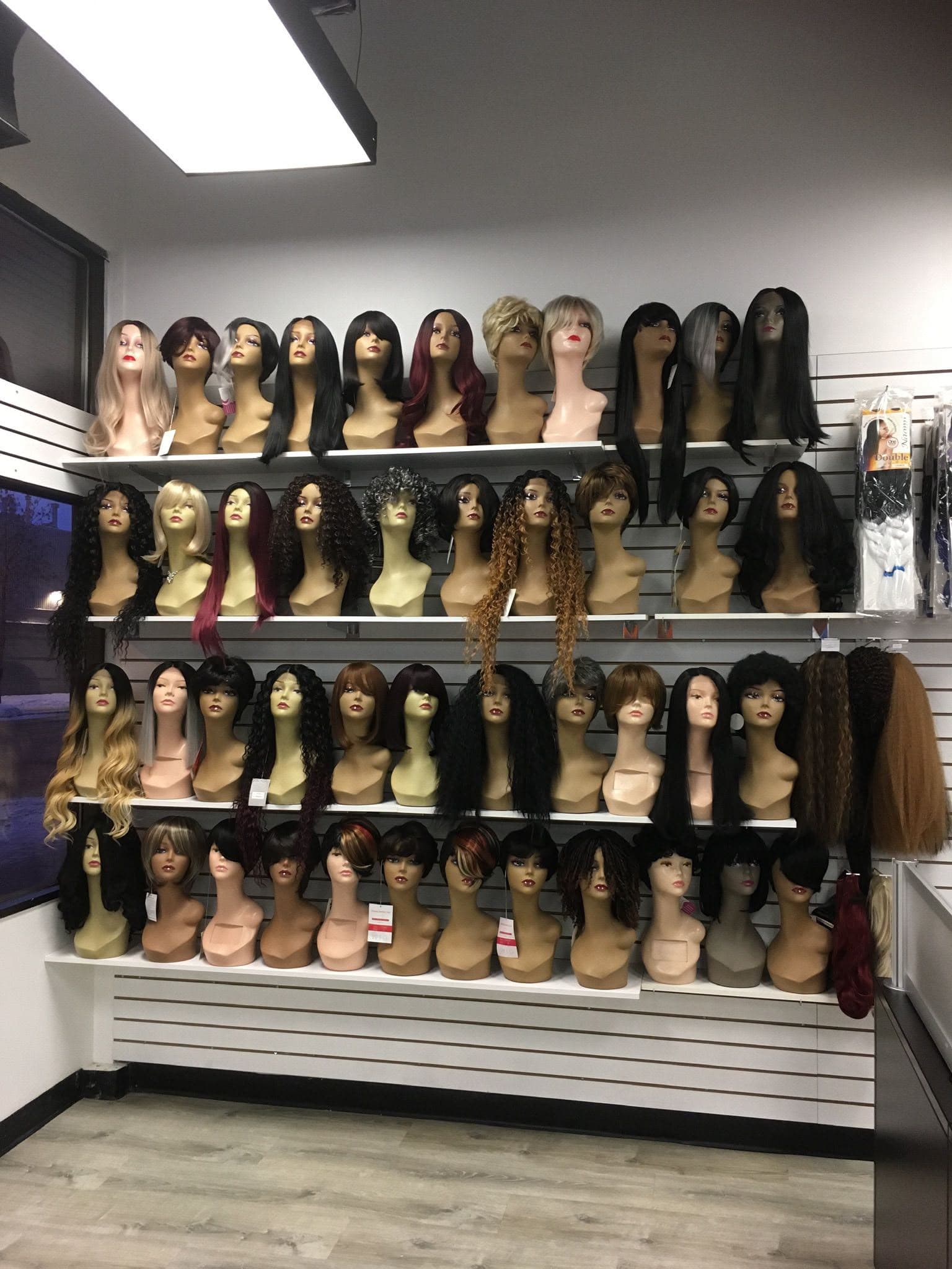 Shelves of styled wigs on mannequin heads lining the studio wall